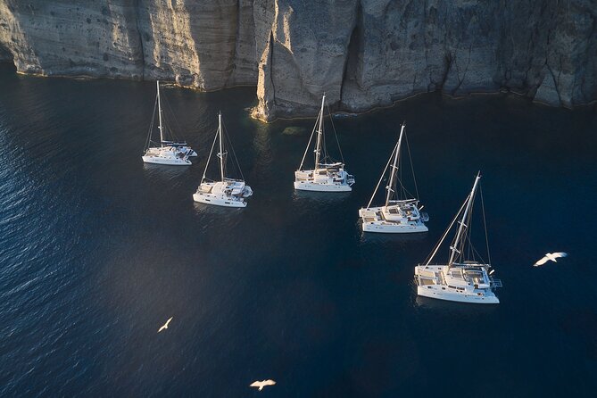 Santorini: Luxury Catamaran Cruise with Fresh Fish BBQ & Drinks - The lighthouse and the southern tip of Santorini